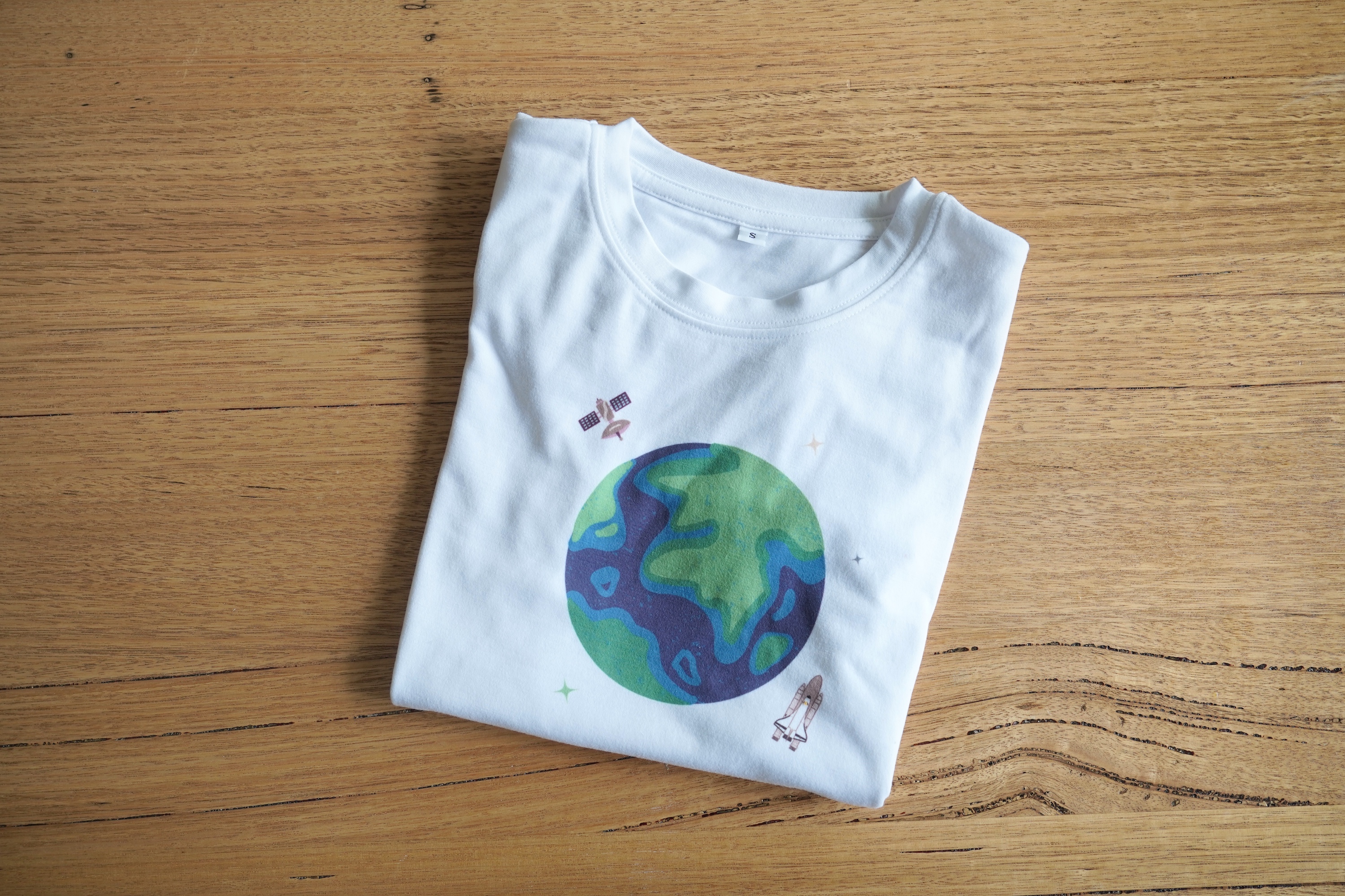 White tshirt with space satellites and rocket around a earth image 